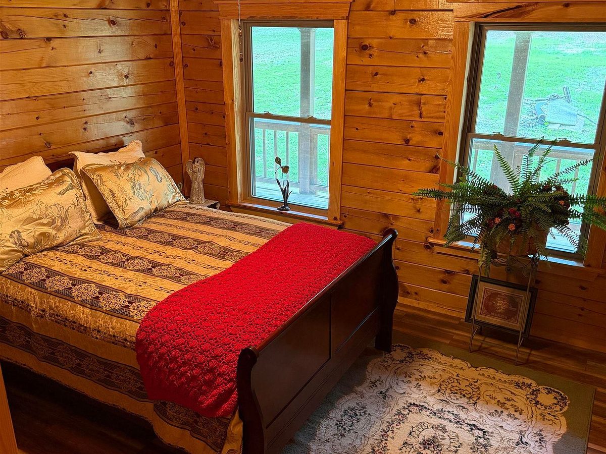 Main bedroom with sleigh bed and forest-view windows at Sugar Creek Cabin