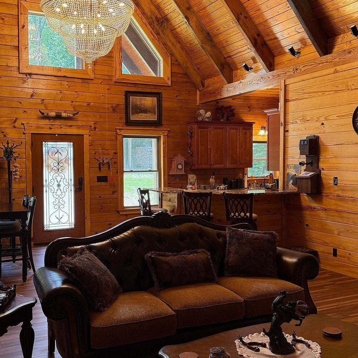 Vaulted great room with exposed beams, leather sofa and the kitchen bar beyond