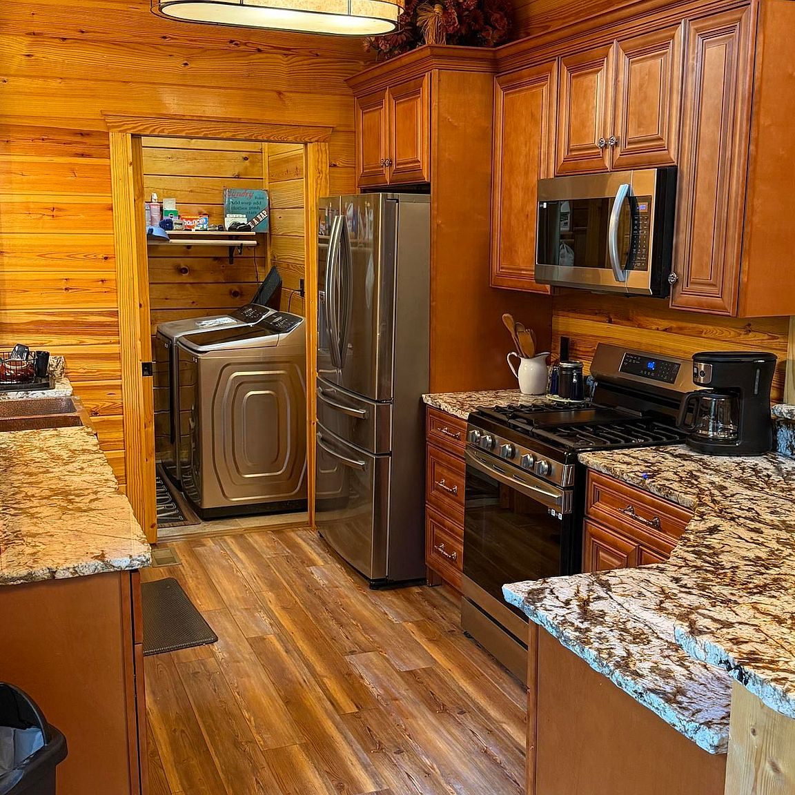 Kitchen with granite counters, gas range, full-size fridge and laundry room beyond